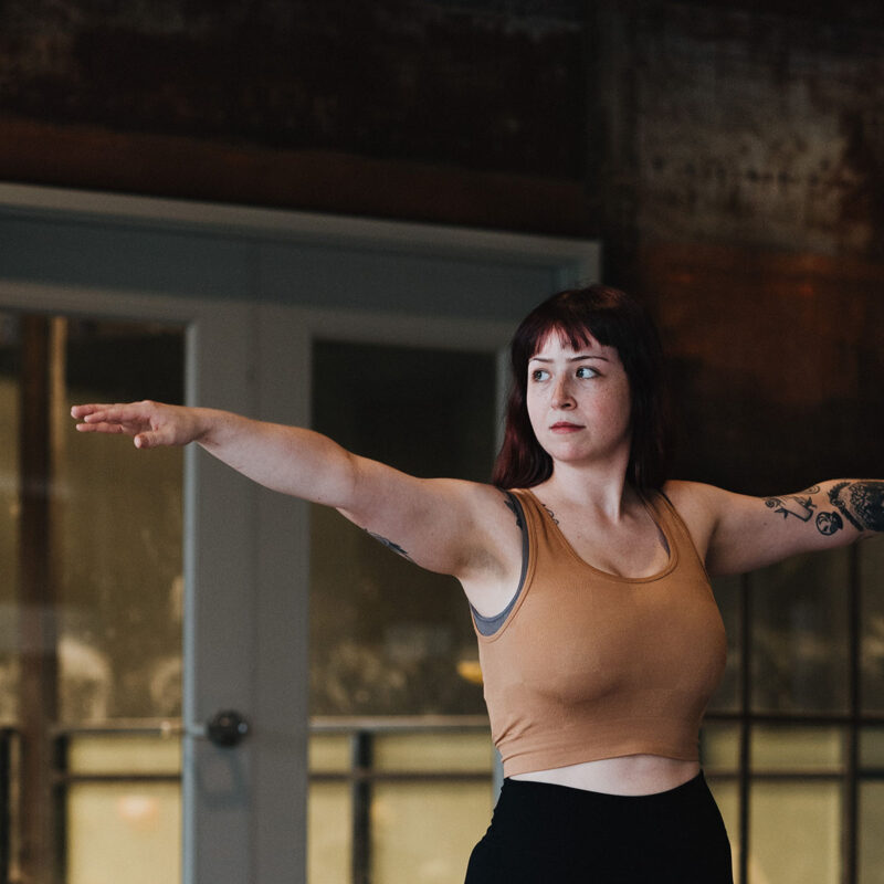 Woman does yoga with an industrial wall behind her.